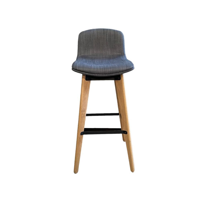 Upholstered grey / blue bar stool with wooden legs and footrest, from the front.