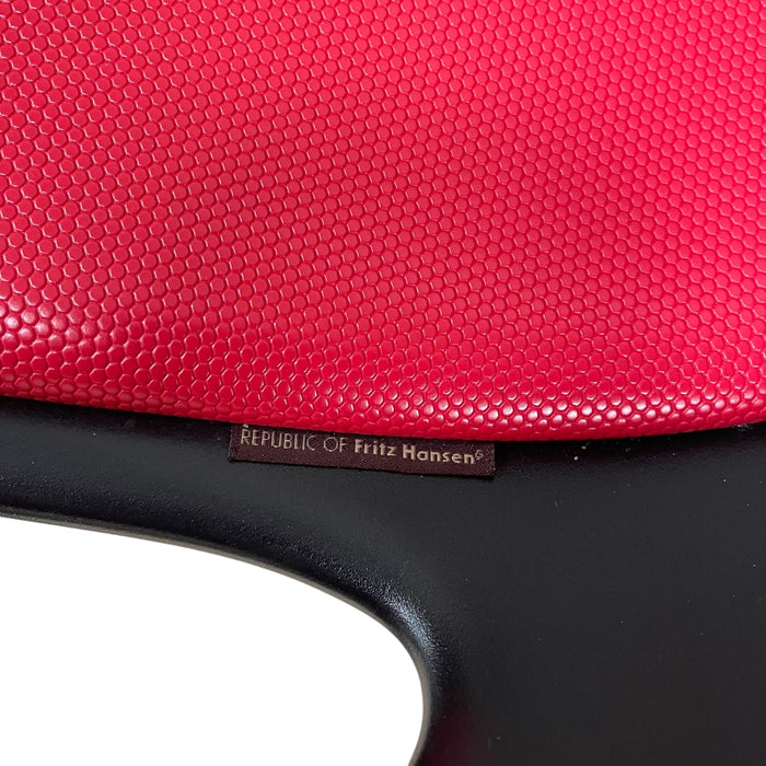 Close up of red and black Fritz Hansen swivel dining chair.