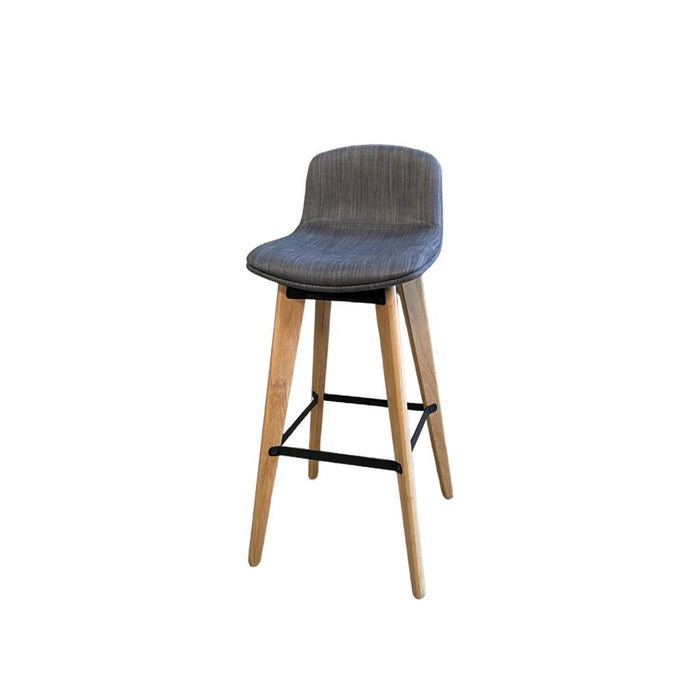 Upholstered grey / blue bar stool with wooden legs and footrest, from the side.