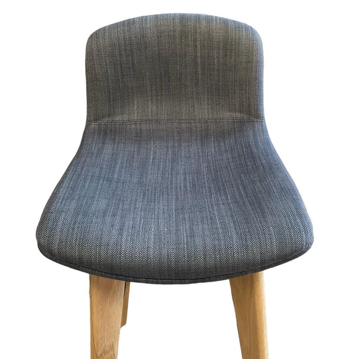 Close up of seat on upholstered grey / blue bar stool with wooden legs and footrest, from the front.
