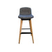 Upholstered grey / blue bar stool with wooden legs and footrest, from the front.