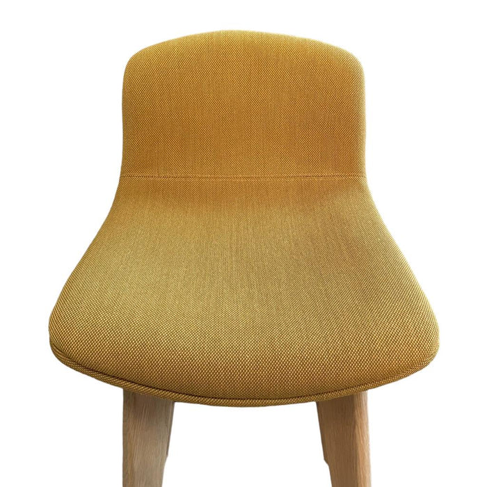 Close up of upholstered yellow bar stools with wooden legs.