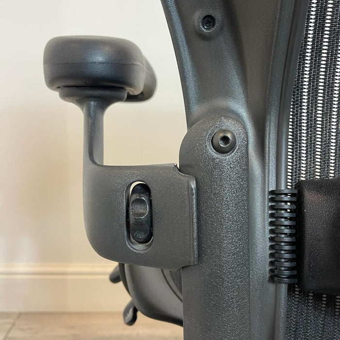 Close up of the mechanisms on the back of a graphite Herman Miller mesh office chair.